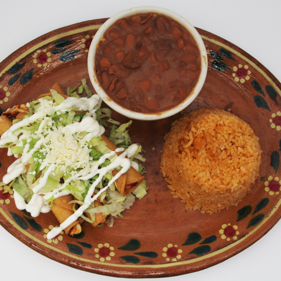 Speedy Tacos and Chicken's Mexican meal with taquitos, rice, and beans on a decorative plate.