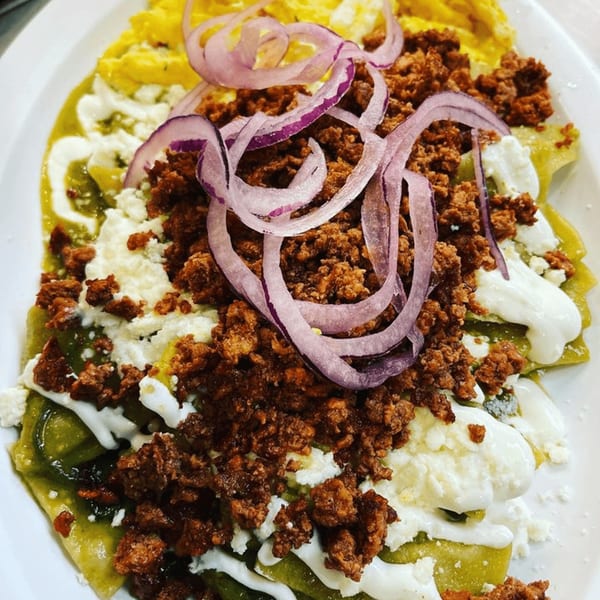 Chilaquiles with green sauce, crumbled chorizo, cotija cheese, sour cream, and red onion.