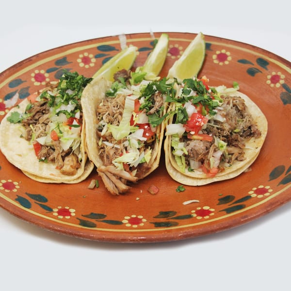 Three Speedy Tacos with shredded meat, pico de gallo, and cilantro, served with lime wedges on a decorative plate.