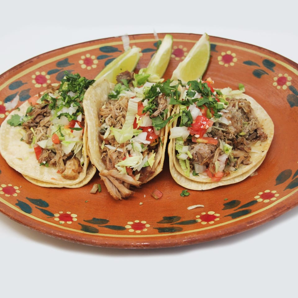 Three Speedy Tacos with shredded meat, pico de gallo, and cilantro, served with lime wedges on a decorative plate.